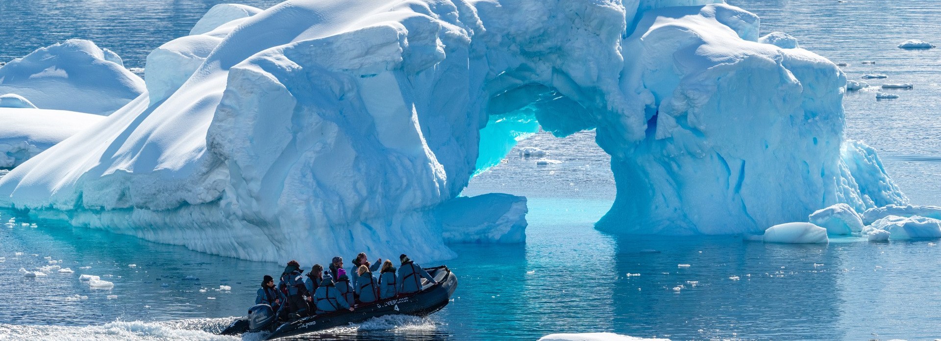 HX Hurtigruten Expeditions Zodiac excursion beside a massive Antarctic iceberg representing Active and Adventure travel microsites