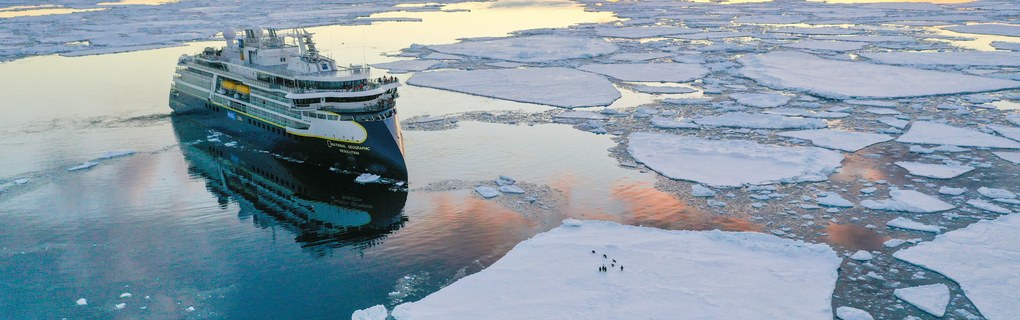National Geographic Lindblad Expeditions ship navigating polar ice floes at sunset through Signature Travel Network preferred partners