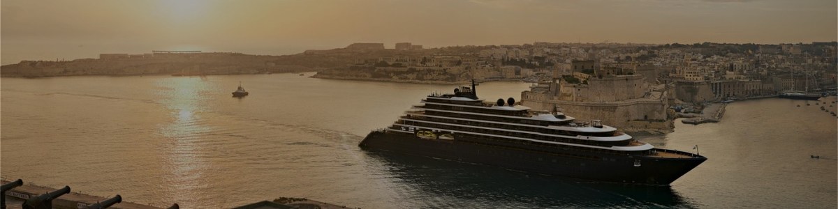 The Ritz-Carlton Yacht Collection superyacht sailing into a Mediterranean harbor for luxury client trip management